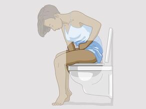 En kvinne sitter på toalettet og holder en arm mellom bena. Armen mellom bena fremheves.